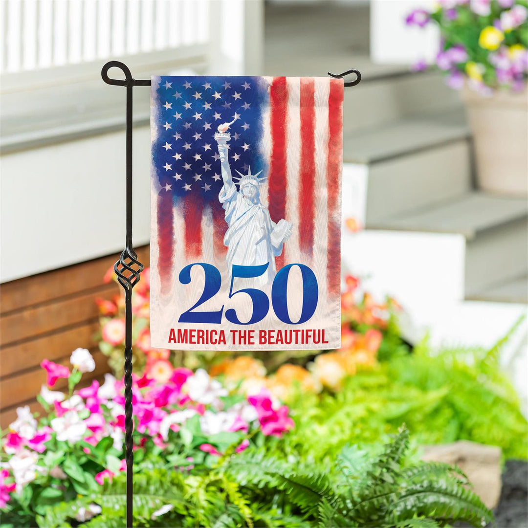 250th Anniversary America The Beautiful Garden Flag on stand in garden with flowers