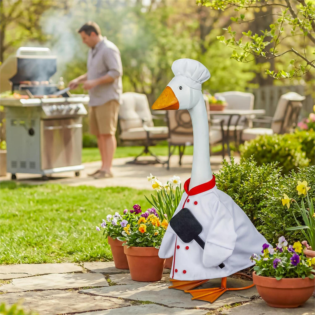 Chef-dressed porch goose beside flowers at a backyard barbecue