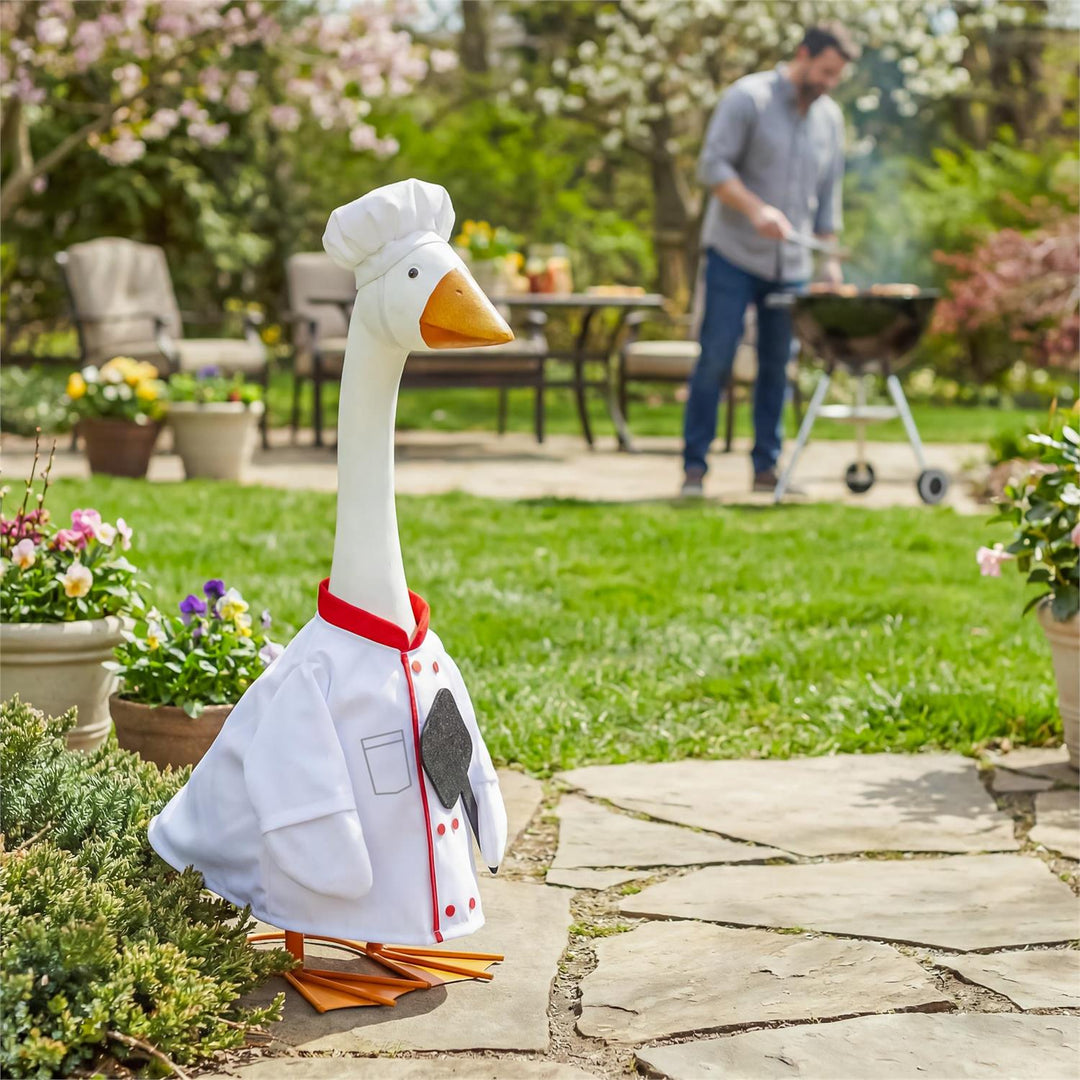 Chef porch goose outfit displayed on a goose beside a garden walkway and grill
