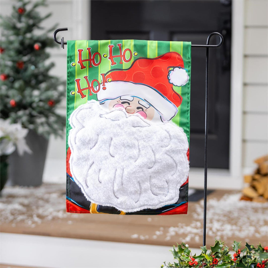 Santa Christmas garden flag displayed on a stand beside a festive porch