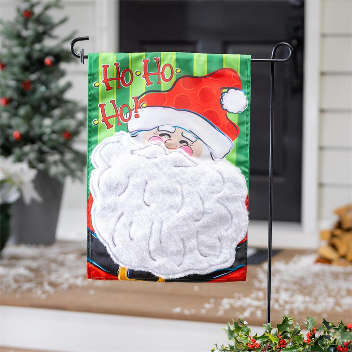 Santa Christmas garden flag displayed on a stand beside a festive porch