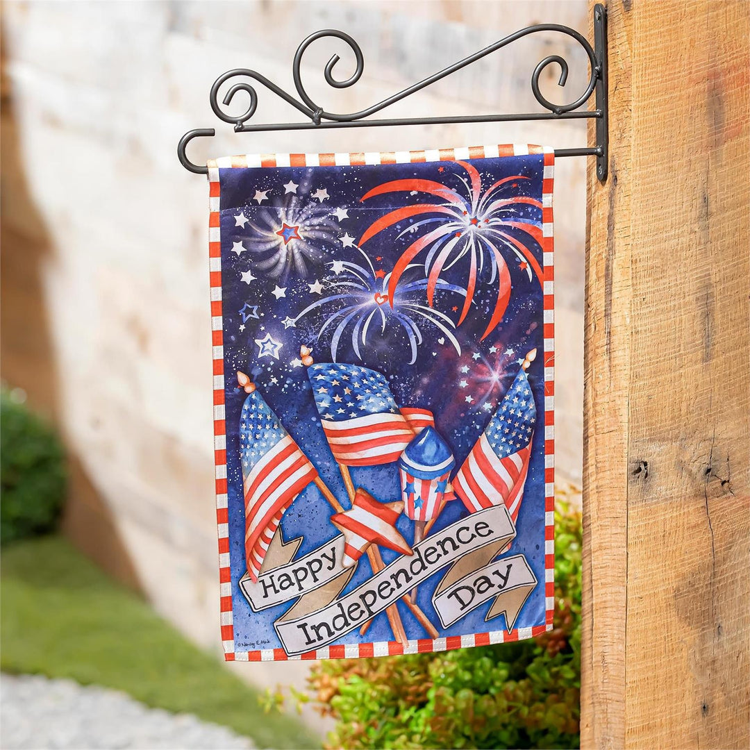 Independence Day Fireworks 2 Sided Garden Flag displayed on a decorative wall bracket showing American flags, firework rockets, and a Happy Independence Day banner on a midnight blue background