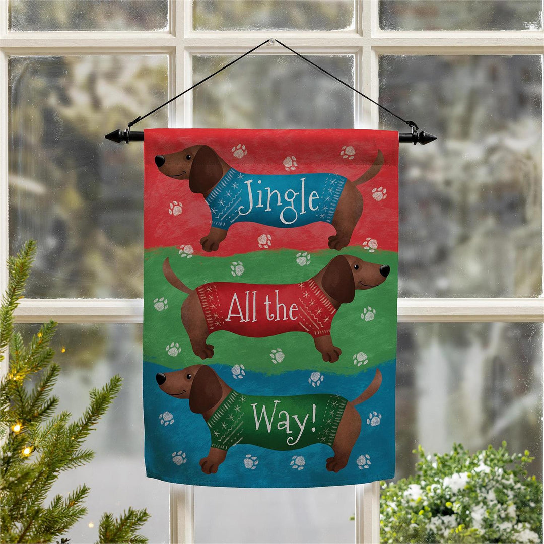 Jingle All the Way dachshund flag hanging in a window beside Christmas greenery
