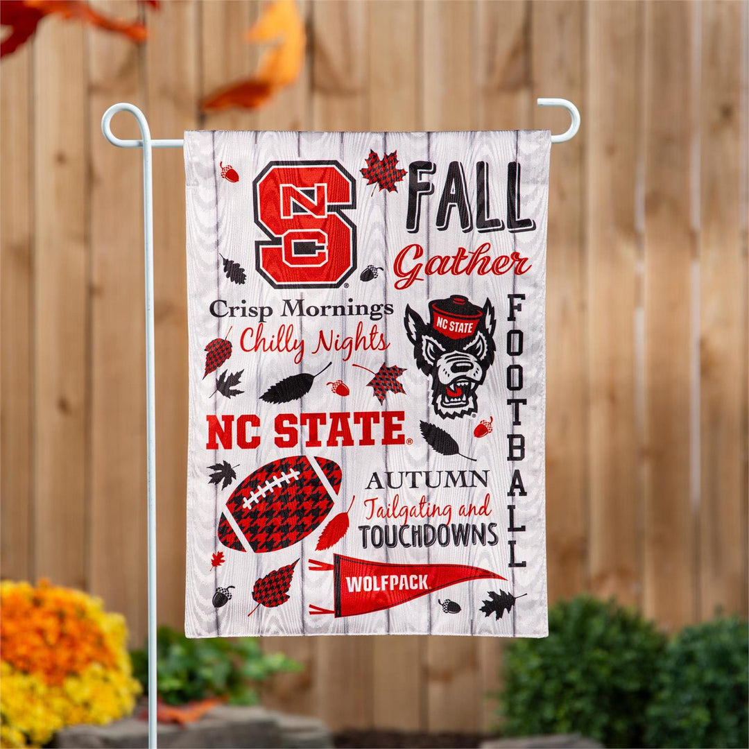 North Carolina State fall garden flag hanging beside a wooden fence
