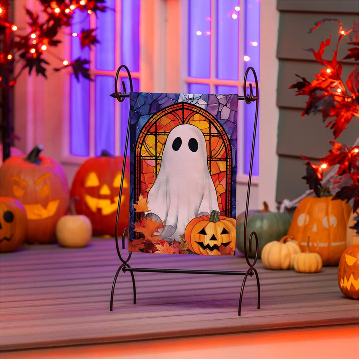 Halloween ghost garden flag displayed on a stand beside pumpkins and fall flowers