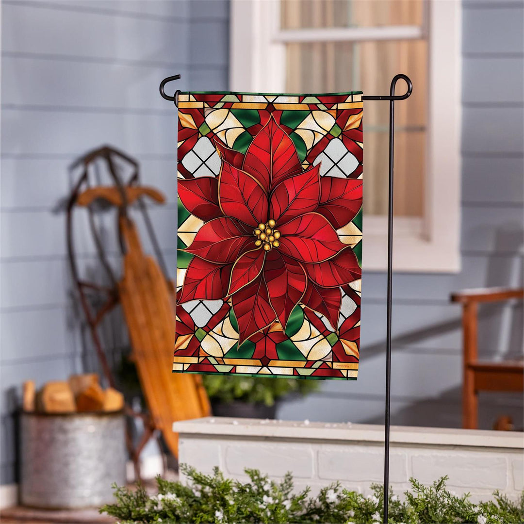 Red poinsettia burlap garden flag displayed on a black garden stand