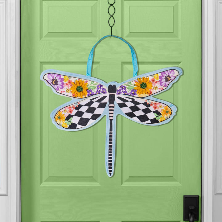 Courtly Check Dragonfly Shaped Door Decor hanging on a green front door showing full dragonfly silhouette with black-and-white check wings and floral upper wings